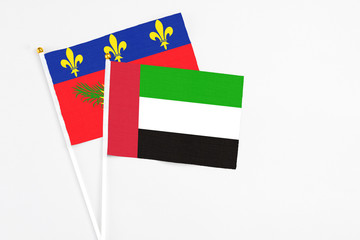 United Arab Emirates and Guadeloupe stick flags on white background. High quality fabric, miniature national flag. Peaceful global concept.White floor for copy space.