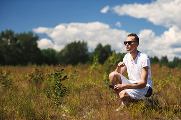 Naklejka na ściany i meble Man sitting in rural field in summer day
