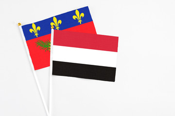 Yemen and Guadeloupe stick flags on white background. High quality fabric, miniature national flag. Peaceful global concept.White floor for copy space.