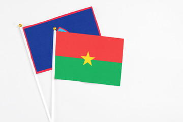 Burkina Faso and Guam stick flags on white background. High quality fabric, miniature national flag. Peaceful global concept.White floor for copy space.