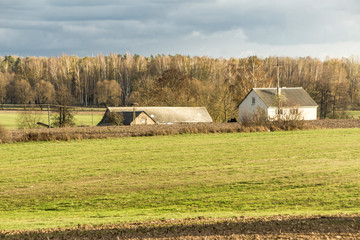 Late autumn. View of a residential building and a barn from the side of a plowed field. Industrial dairy farm. Podlasie. Poland.