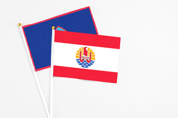 French Polynesia and Guam stick flags on white background. High quality fabric, miniature national flag. Peaceful global concept.White floor for copy space.