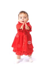 Enthusiastic baby girl in red child dress and white socks standing and catching soap bubbles. Light background