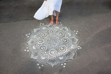 girl's bare feet and the hem of a white dress on the background of asphalt a chalk pattern