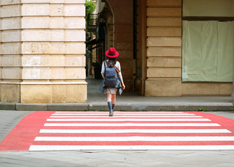 Young Woman in Red Hat Walking on Red and White Crosswalk 
