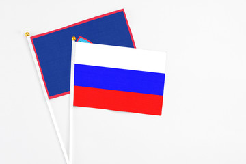 Russia and Guam stick flags on white background. High quality fabric, miniature national flag. Peaceful global concept.White floor for copy space.