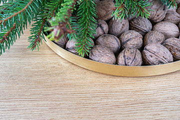 Merry Christmas decoration  with walnuts on a natural oak wooden background. A natural perspective composition in brown and gold  colors. 