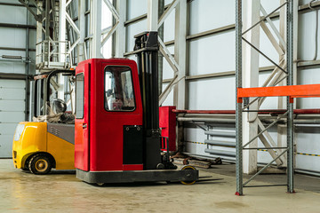 Red and yellow compact forklift trucks in a industrial warehouse building
