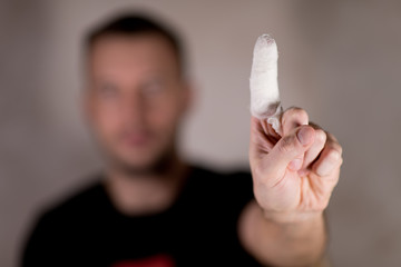 the man show the index finger up gesture and this finger is bandaged