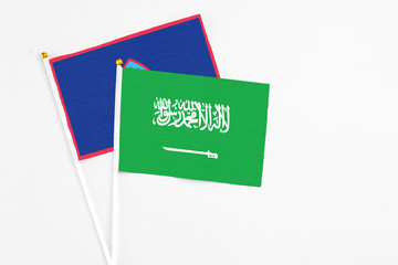 Saudi Arabia and Guam stick flags on white background. High quality fabric, miniature national flag. Peaceful global concept.White floor for copy space.