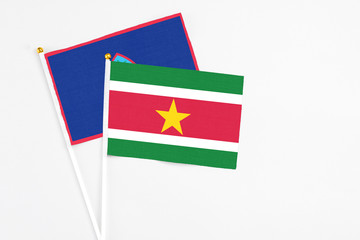Suriname and Guam stick flags on white background. High quality fabric, miniature national flag. Peaceful global concept.White floor for copy space.