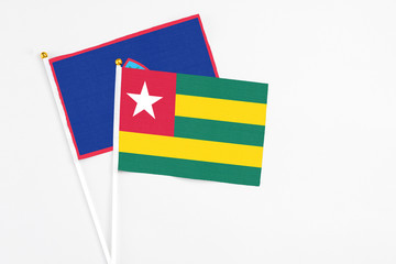 Togo and Guam stick flags on white background. High quality fabric, miniature national flag. Peaceful global concept.White floor for copy space.