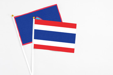 Thailand and Guam stick flags on white background. High quality fabric, miniature national flag. Peaceful global concept.White floor for copy space.