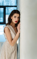 Beautiful girl bride in front of the camera, designer dress, sensual look. Vertical photograph.