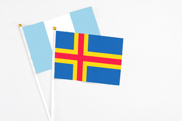 Aland Islands and Guatemala stick flags on white background. High quality fabric, miniature national flag. Peaceful global concept.White floor for copy space.