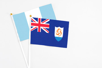 Fototapeta premium Anguilla and Guatemala stick flags on white background. High quality fabric, miniature national flag. Peaceful global concept.White floor for copy space.