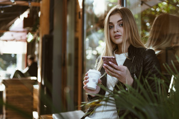 blonde with chiseled features, inquiringly proudly looked up from the phone and looking at someone against the background of the cafe