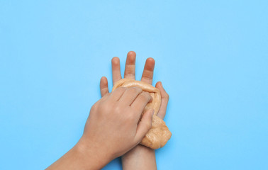 Child hands with slime on blue background.