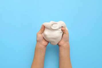 Child hands with slime on blue background.