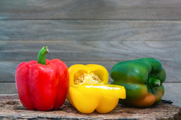 Red, yellow and green peppers (Sweet peeper or bell pepper or Capcicum.)  on wooden with brown background.