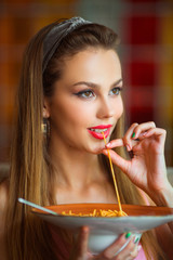 beautiful young woman with makeup eats spaghetti in a restaurant