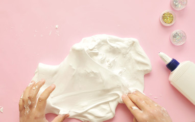 Child hands with home-made slime.  Baby makes a home made slime with glue and glitters on background.