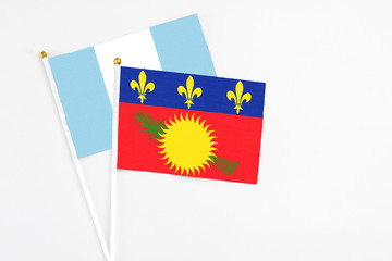 Guadeloupe and Guatemala stick flags on white background. High quality fabric, miniature national flag. Peaceful global concept.White floor for copy space.