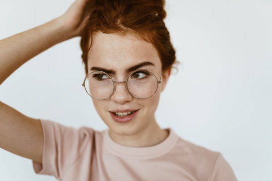 schoolgirl looks suspiciously incredulously - mockingly through glasses for sight, raising an eyebrow and holding her hair with her hand on the crown