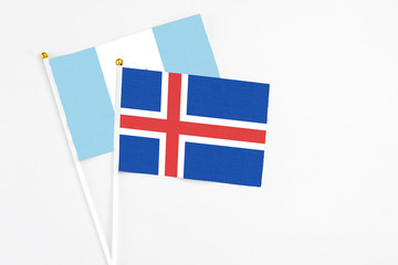 Obraz premium Iceland and Guatemala stick flags on white background. High quality fabric, miniature national flag. Peaceful global concept.White floor for copy space.
