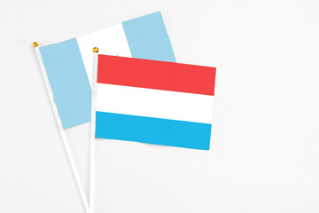 Luxembourg and Guatemala stick flags on white background. High quality fabric, miniature national flag. Peaceful global concept.White floor for copy space.