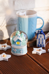 snow Christmas globe with a house inside on the background of a blue mug.