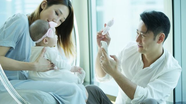 Chinese Asian parents baby enjoying smartphone wireless technology