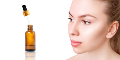 Cosmetics oil in bottle near beautiful face of young woman.