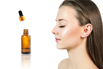 Cosmetics oil in bottle near beautiful face of young woman.