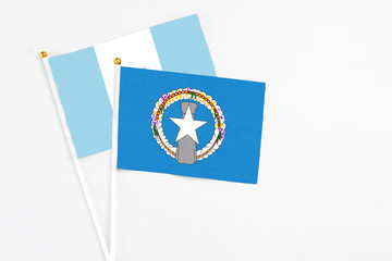 Northern Mariana Islands and Guatemala stick flags on white background. High quality fabric, miniature national flag. Peaceful global concept.White floor for copy space.