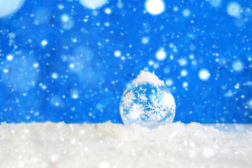Fototapeta na wymiar Christmas ball on a background of snowflakes. Christmas or New Year card, bokeh effect.