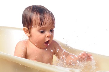 Surprised little baby girl play with enthusiasm with splashes water in the bath. Game in bathtub. Isolated on background