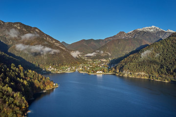 Obraz na płótnie Canvas Panoramic view of the mountains and lake Pieve di Ledro, Italy. Autumn season, the reflection in the water of the mountains, trees, blue sky