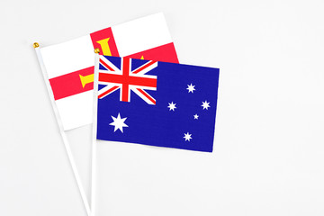 Fototapeta premium Australia and Guernsey stick flags on white background. High quality fabric, miniature national flag. Peaceful global concept.White floor for copy space.