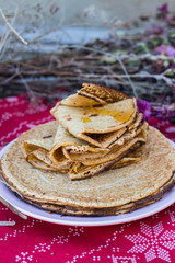 Crepes or traditional Russian pancakes with honey on Christmas tablecloth. Homemade.