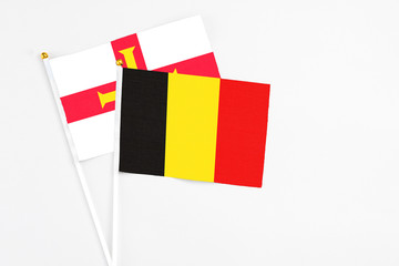 Belgium and Guernsey stick flags on white background. High quality fabric, miniature national flag. Peaceful global concept.White floor for copy space.