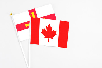 Canada and Guernsey stick flags on white background. High quality fabric, miniature national flag. Peaceful global concept.White floor for copy space.