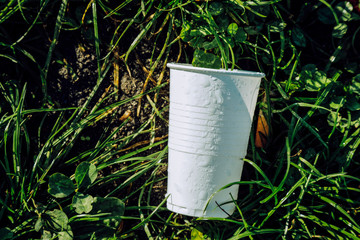 white plastic cup lay on grass, global environment pollution, 
