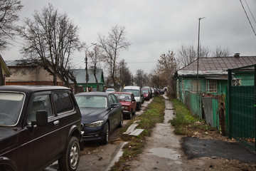 Parked cars on the road in the village, old houses