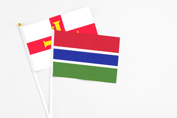 Gambia and Guernsey stick flags on white background. High quality fabric, miniature national flag. Peaceful global concept.White floor for copy space.