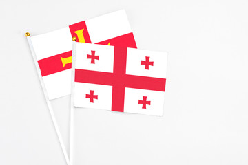 Georgia and Guernsey stick flags on white background. High quality fabric, miniature national flag. Peaceful global concept.White floor for copy space.