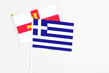 Obraz premium Greece and Guernsey stick flags on white background. High quality fabric, miniature national flag. Peaceful global concept.White floor for copy space.
