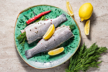 Raw organic sea bass with spices and herbs on a big colorful plate top view. Healthy and organic food concept.