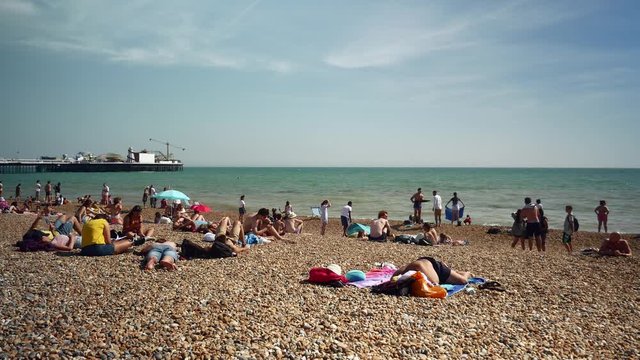 Many people relax and sunbath on the public beach at Brighton pier 4k