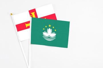 Macao and Guernsey stick flags on white background. High quality fabric, miniature national flag. Peaceful global concept.White floor for copy space.
